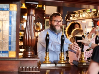 Landlord serving a customer  a pint of stout