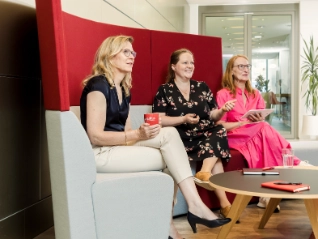 three women having a chat on a couch in the office
