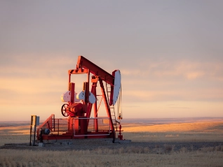 Pump jack in an oil field at sunset