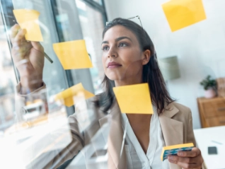 Female planning on a clear screen using sticky notes