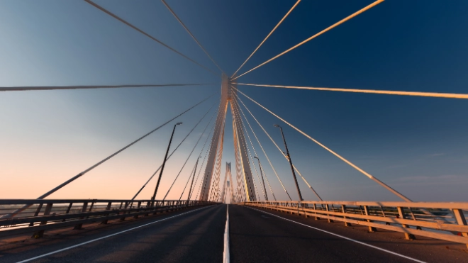 A suspension bridge with an empty road at sunset