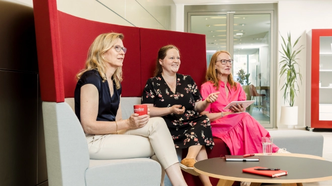 three women having a chat on a couch in the office