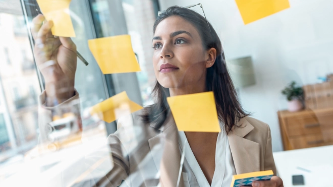 Female planning on a clear screen using sticky notes