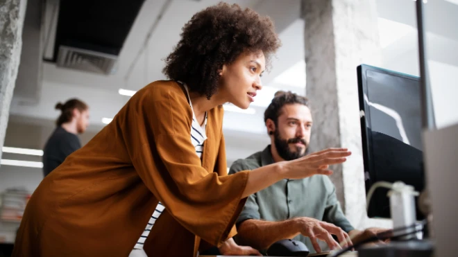 Two employees having a discussion at a desk