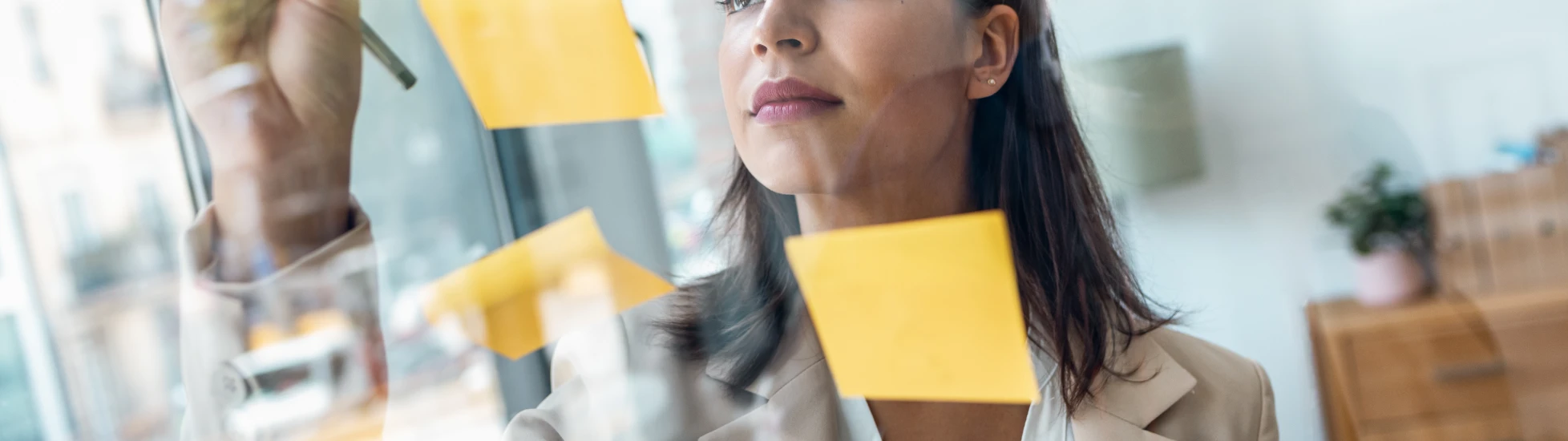 Female planning on a clear screen using sticky notes