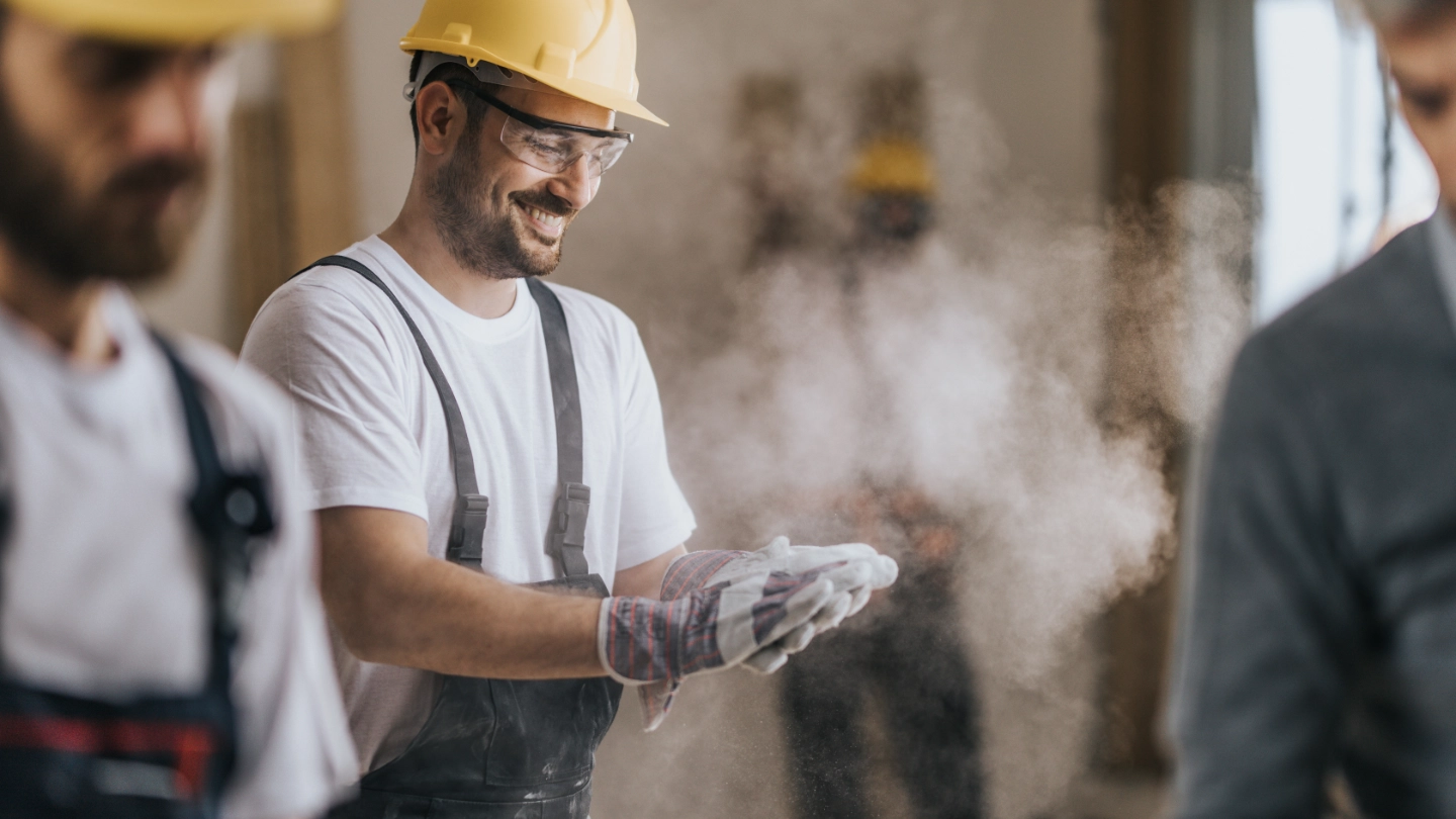 Happy construction worker with dusty gloves