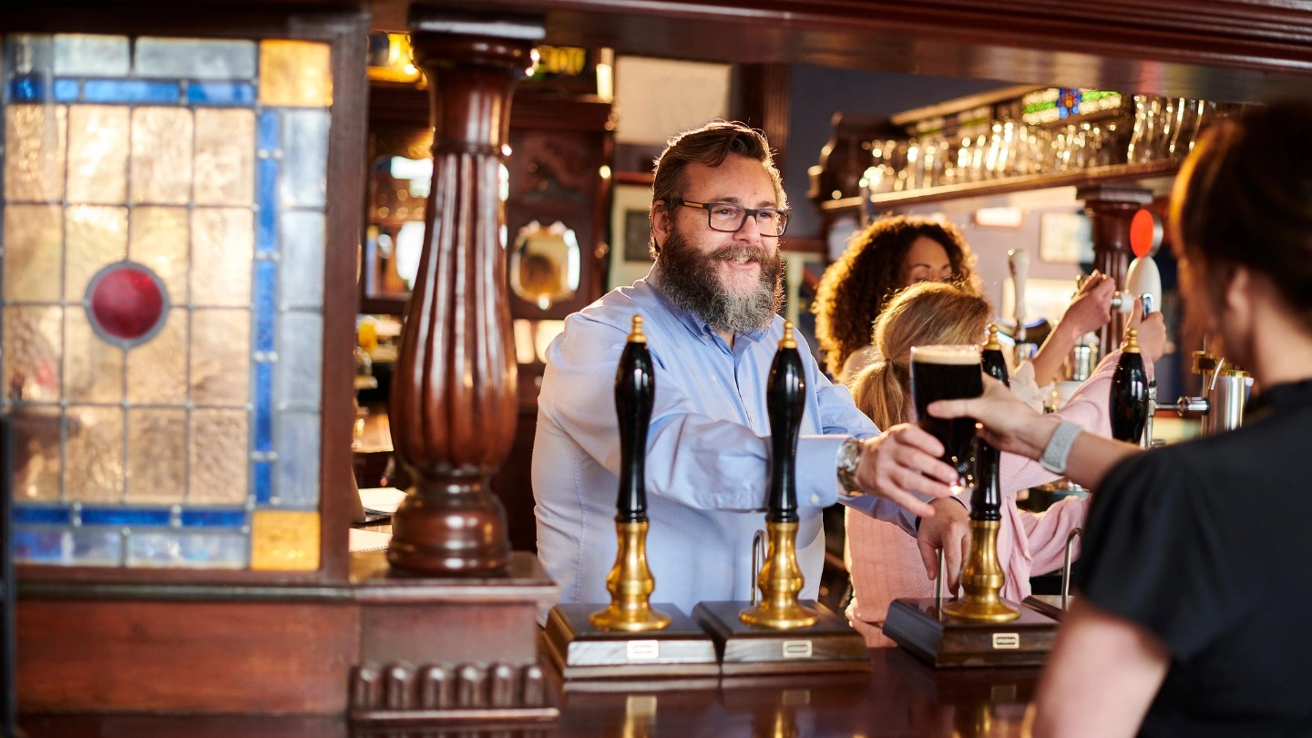 Landlord serving a customer  a pint of stout