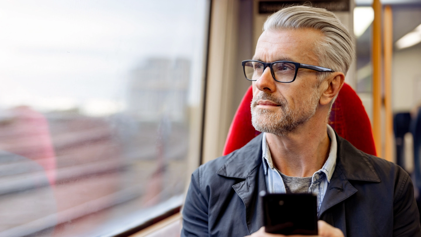 man on a train holding a mobile phone