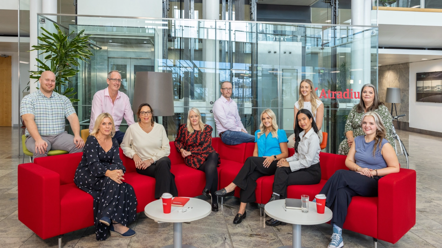 CST group_DS_6990 A group shot of the Atradius CST team, they are sat on a red sofa together in the atrium of the Cardiff office