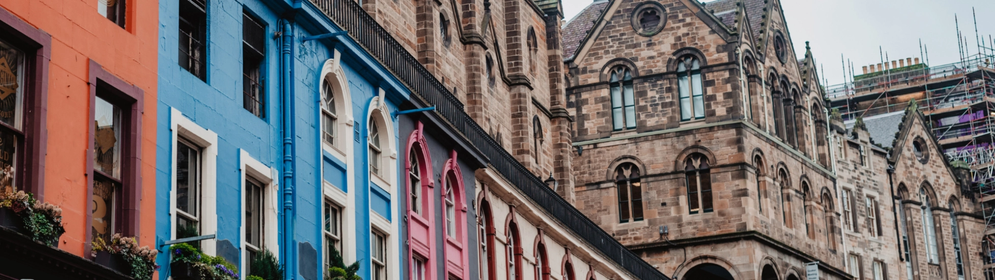 Edinburgh street with colourful shop fronts and a cathedral in the background