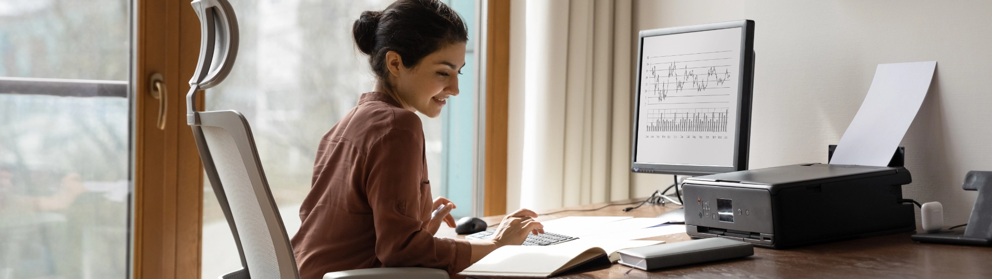 woman behind desk working on a computer