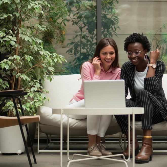 women colleagues discussing business plan in office with laptop