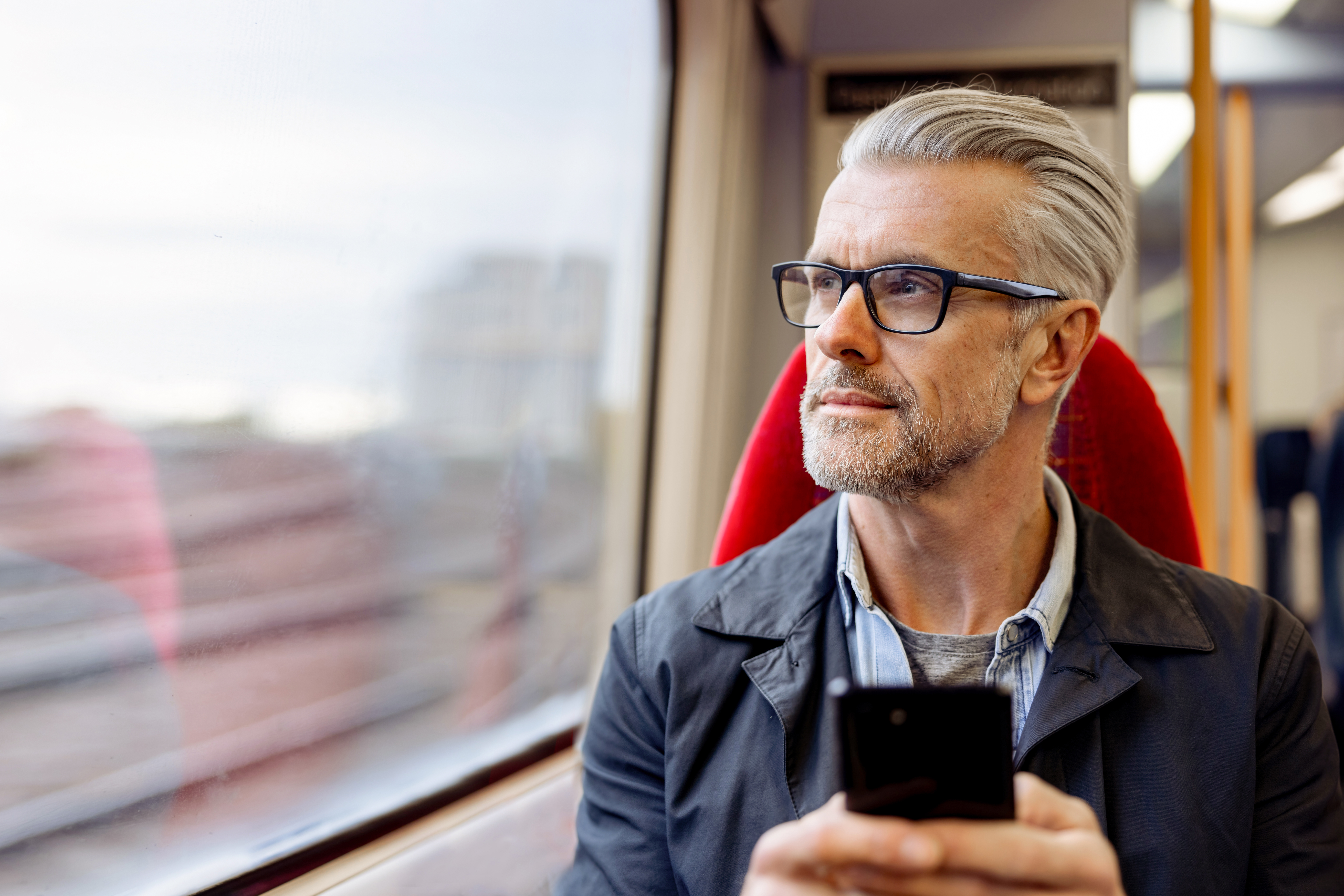 Man on train checking payment practices reporting on mobile device